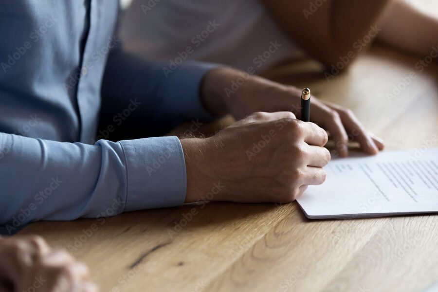 hand holding a pen writing legal document