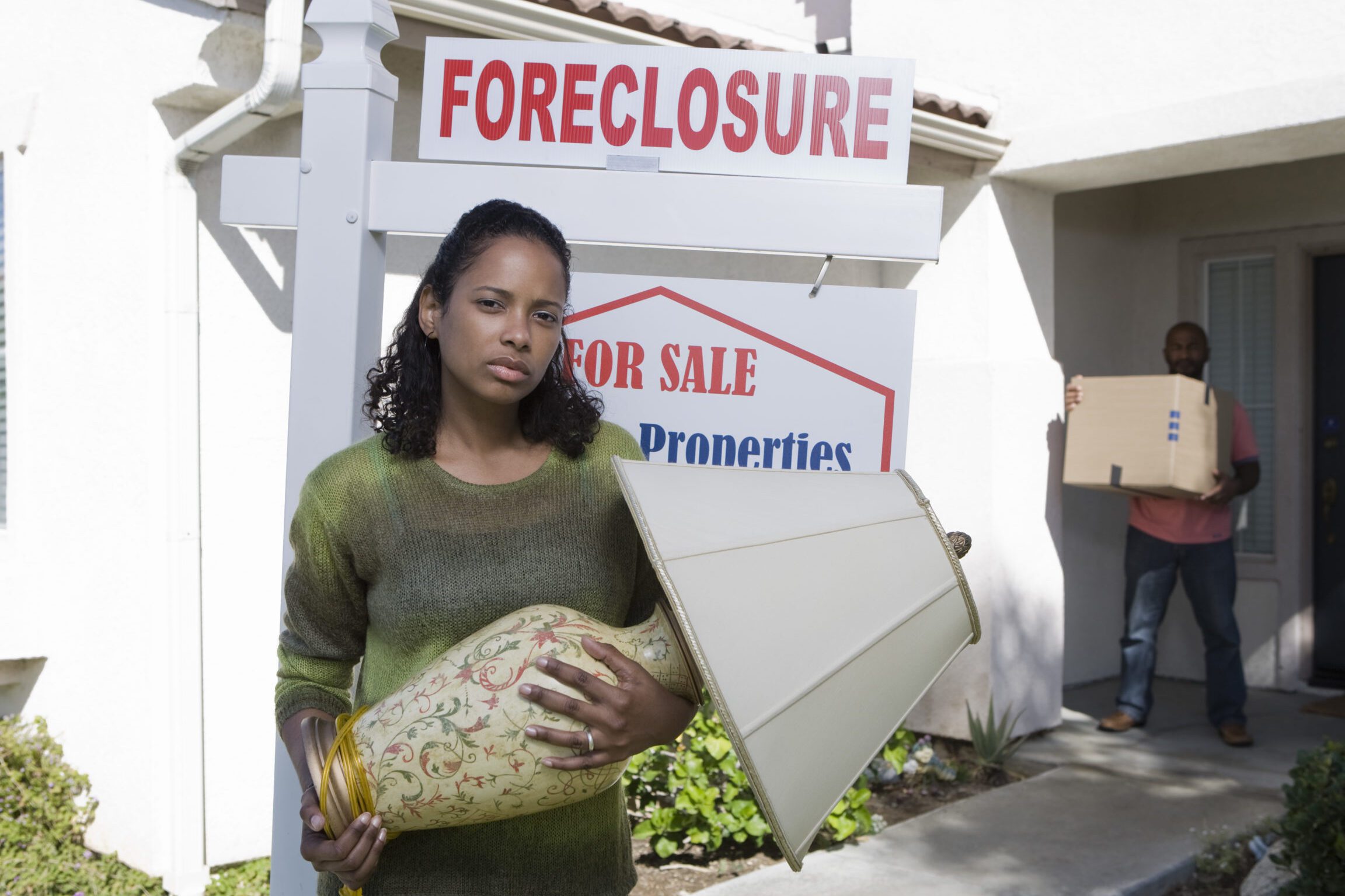 person holding foreclosure sign outside their home