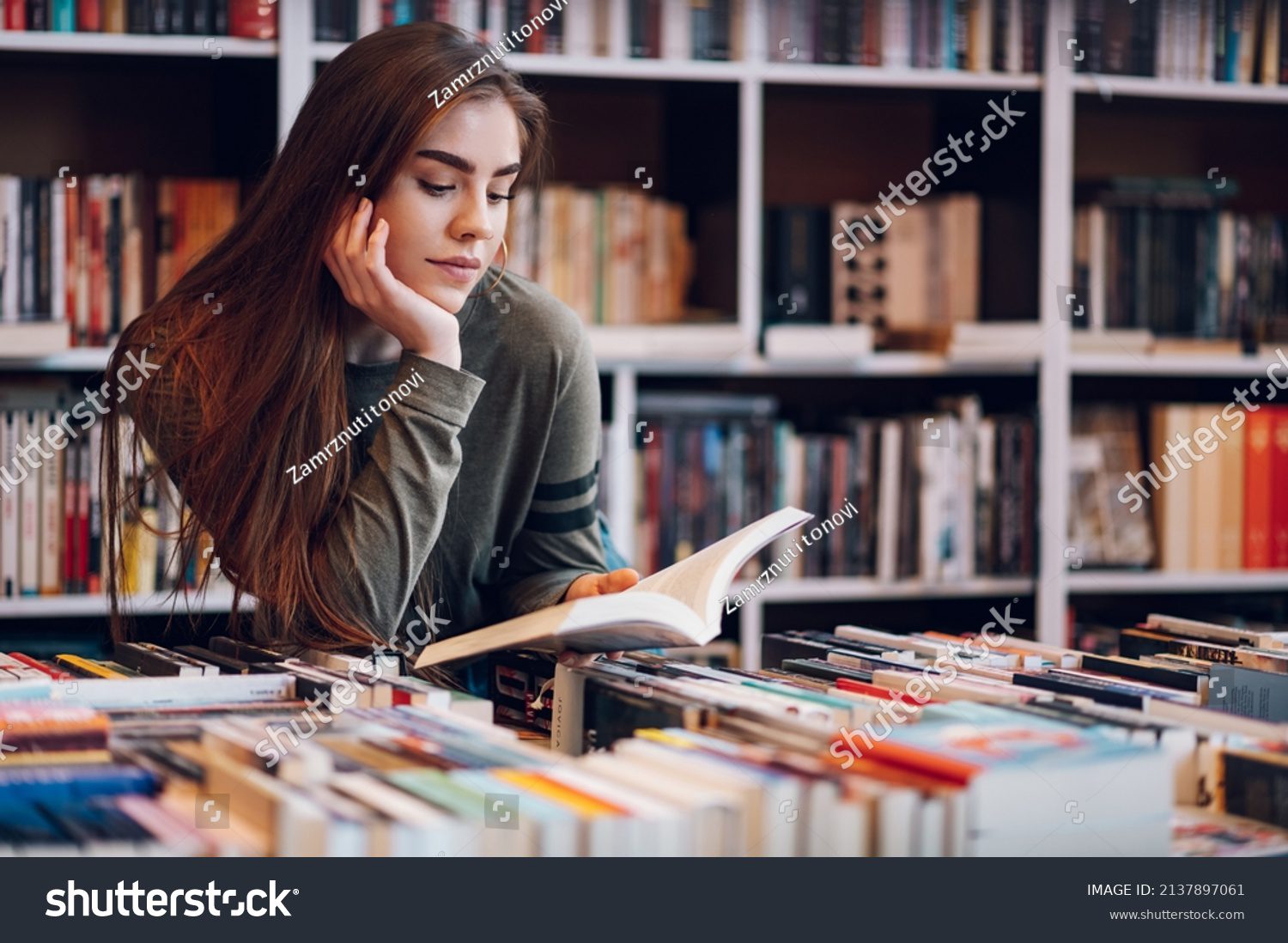 stock photo young female customer reading a book in bookstore while buying some good literature woman picking 2137897061
