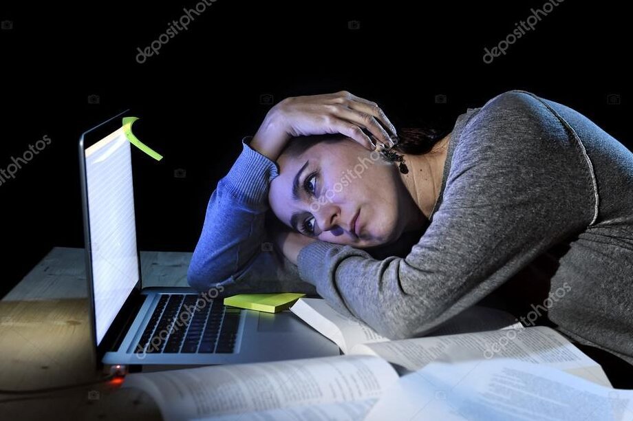 student studying late at night with books and laptop